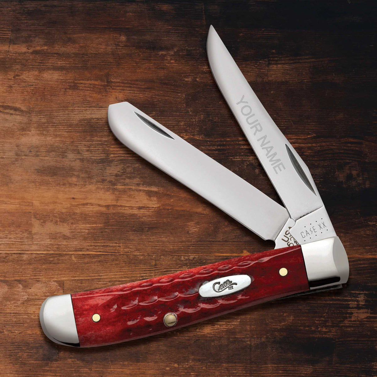 Red engraved Case knife sitting on a wooden surface.