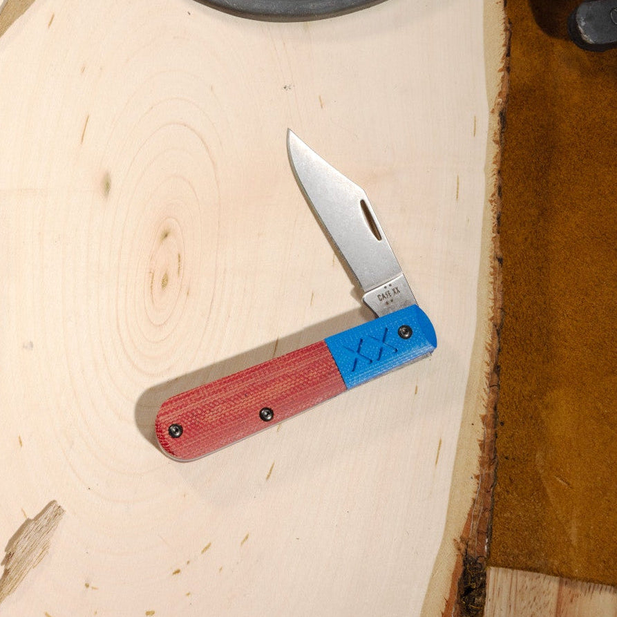 Case knife with a red and blue handle on a wooden surface.