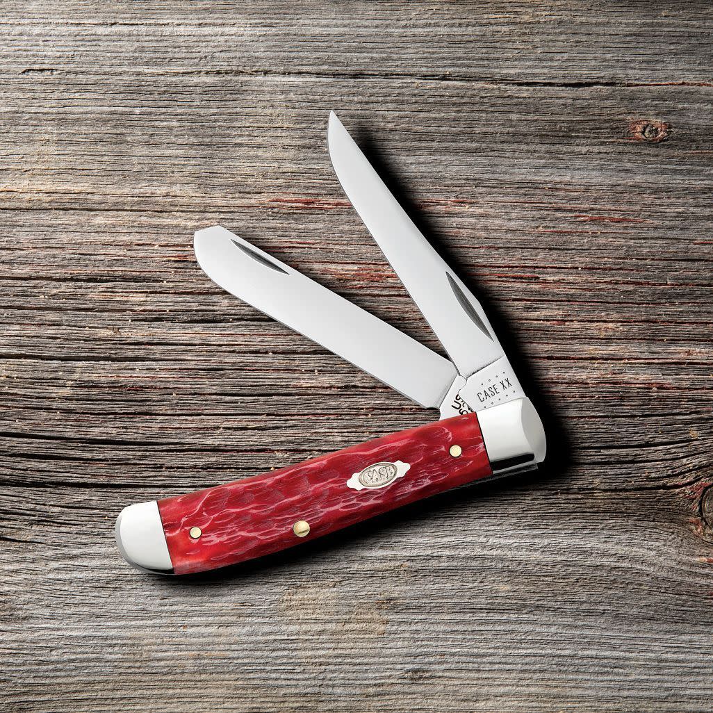 Peach Seed Jig Dark Red Bone CS Mini Trapper Knife on Wooden Background