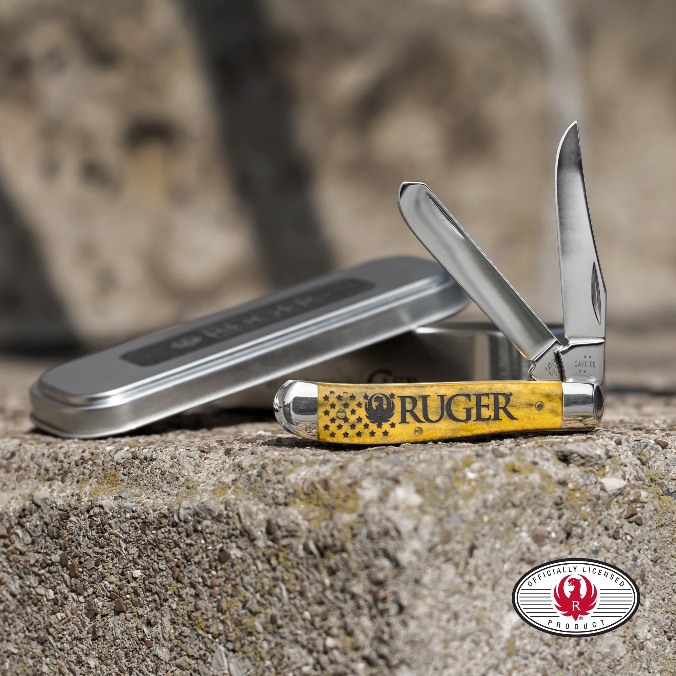 Yellow Case knife with the RUGER logo on the front sitting on a rocky surface.