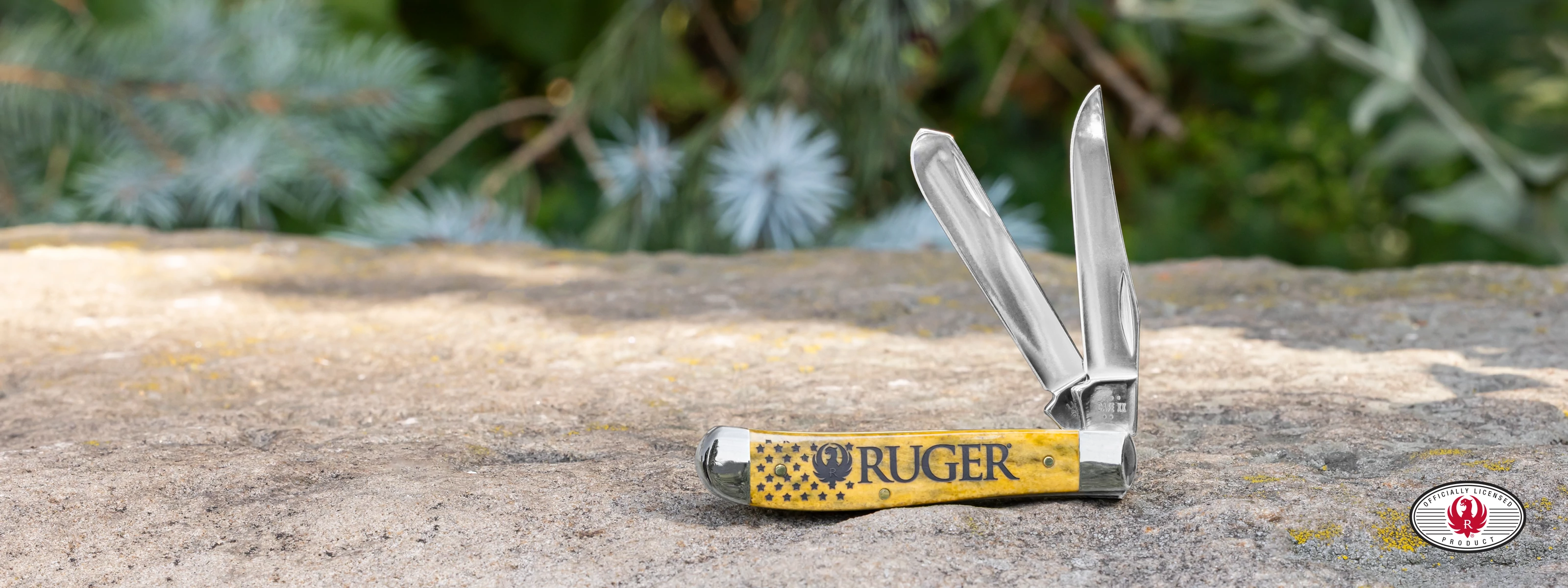 Yellow Case knife with the RUGER logo on the front sitting on a rocky surface.