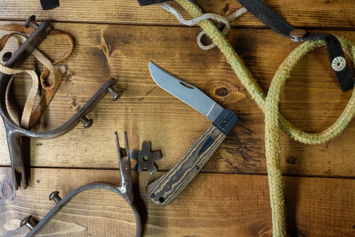 Case knife with a brown handle on a woden surface with a rope in the background.