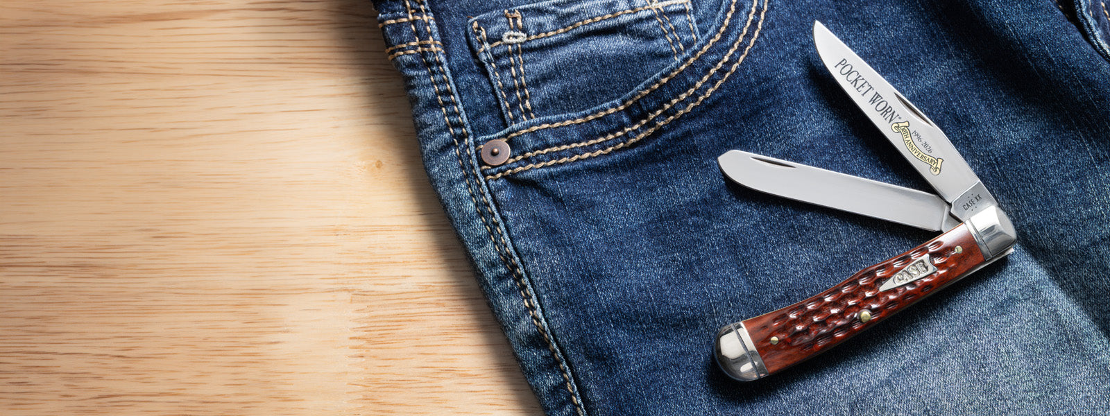 Brown Case knife on a pair of jeans with a wooden background
