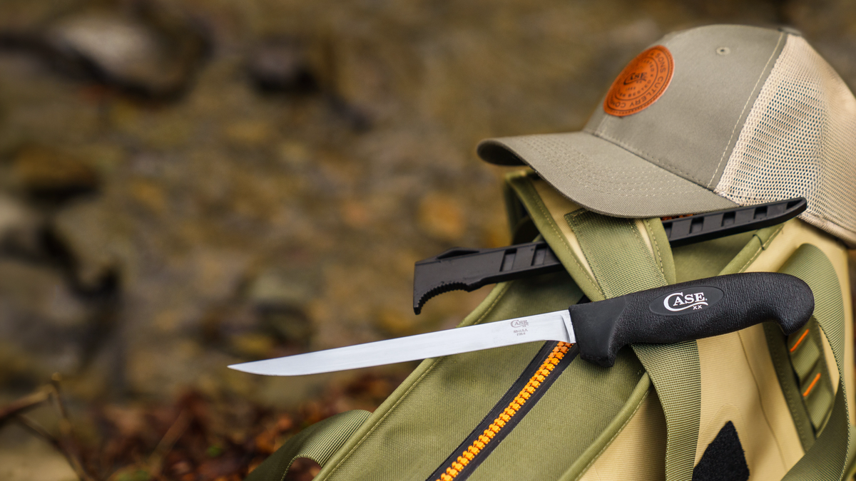 Case knife with a black handle sitting on a green bag. 