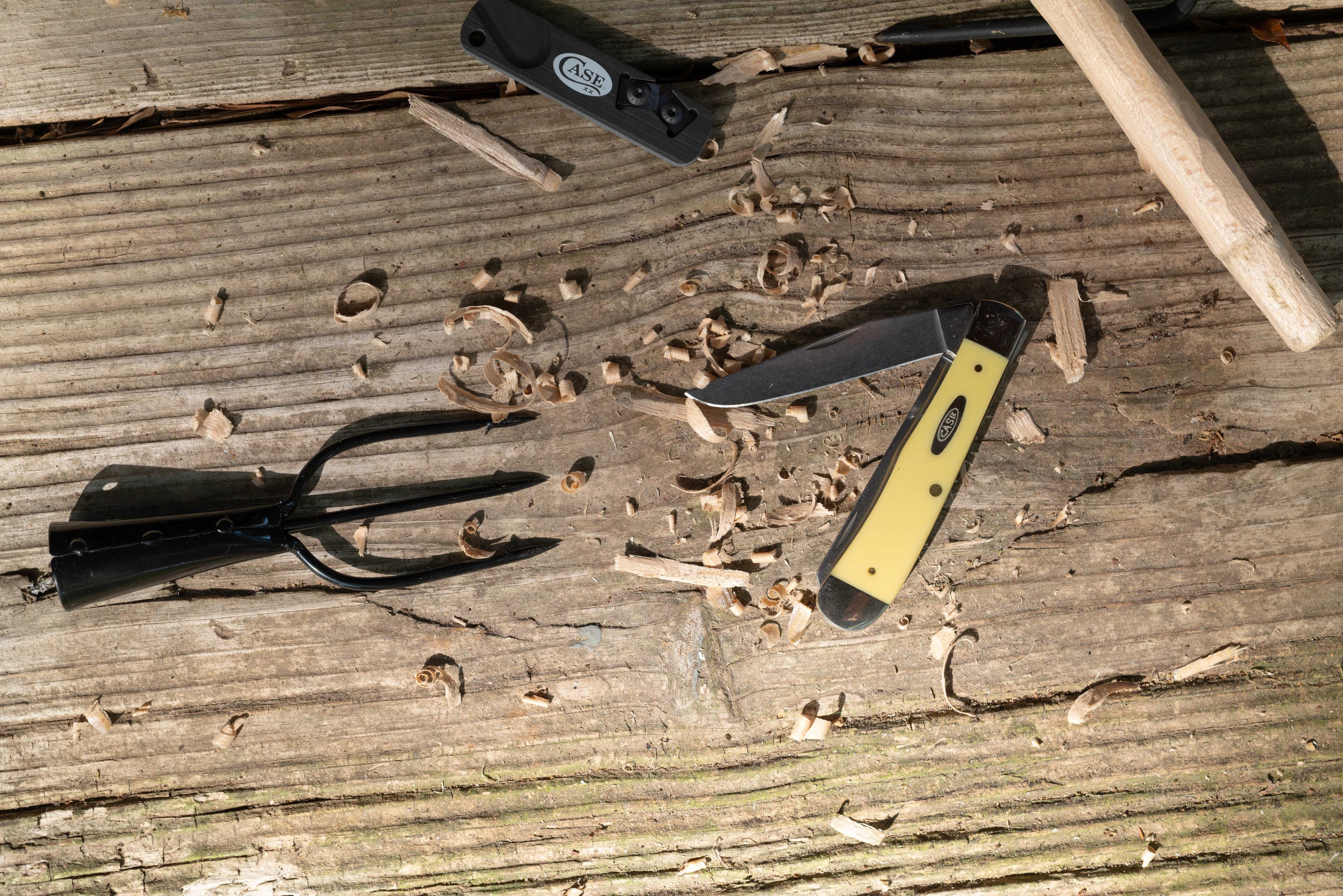 Yellow Case knife on a wooden surface with wood shavings laying around.