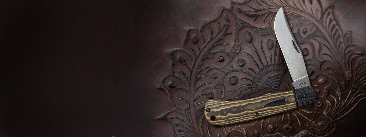 Brown Case knife on a dark brown background with an etched design.