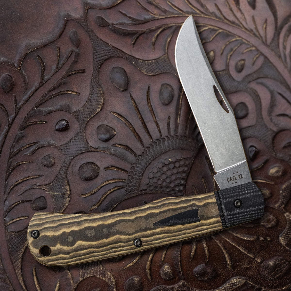 Brown Case knife on a dark brown background with an etched design.