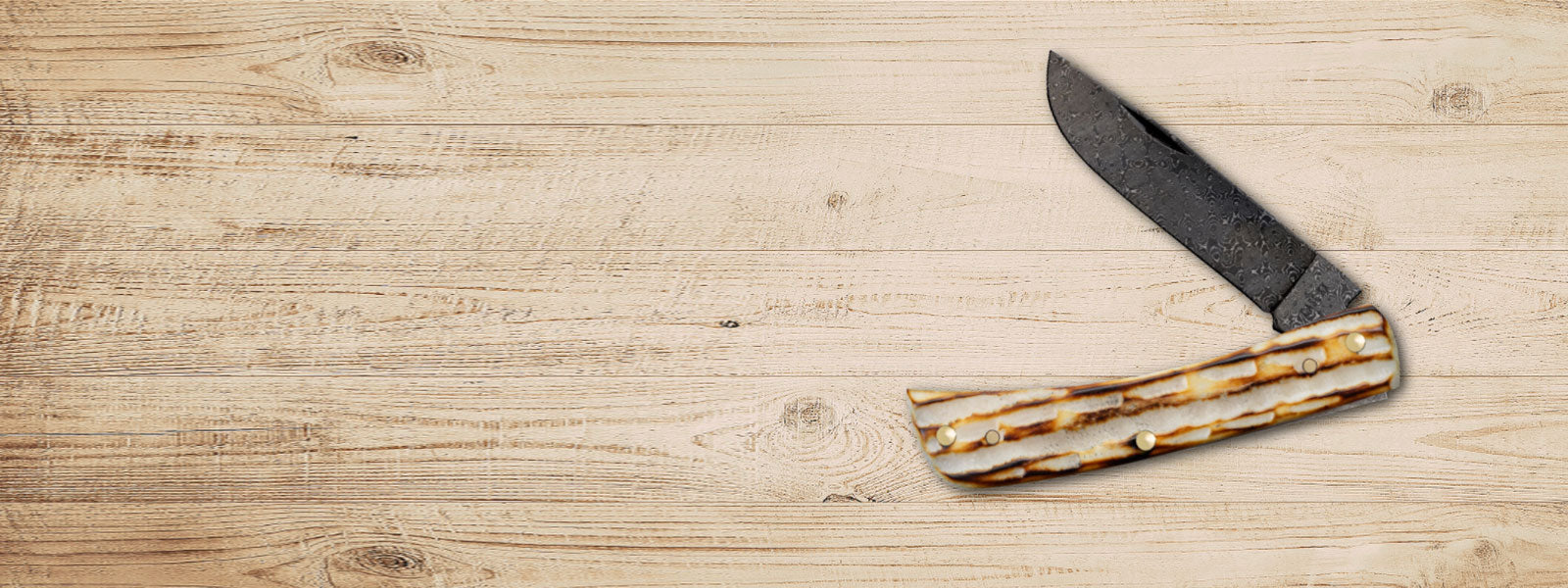 Deep Canyon Burnt Natural Bone knife on a wood plank background.