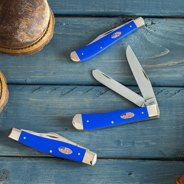 Brown leather boots and gloves with Case knives on a wooden surface.