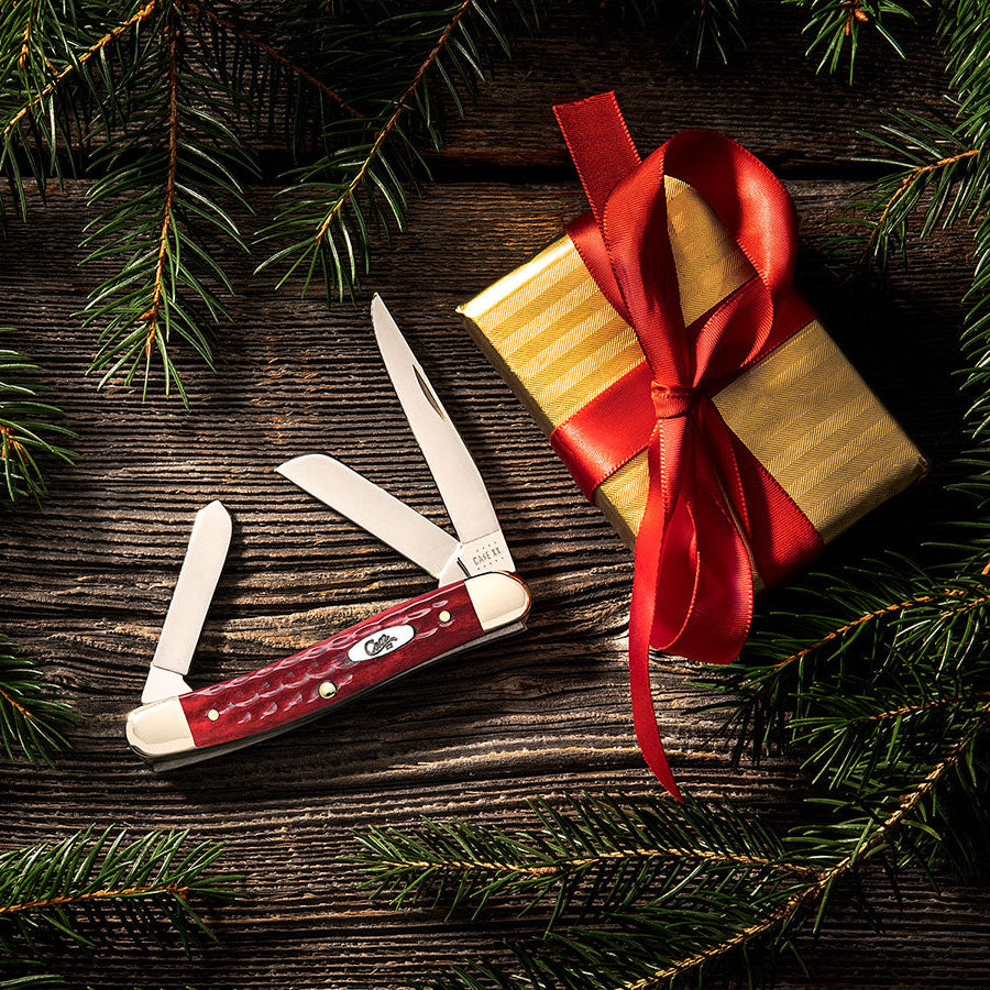  A red Case knife with a gift to the right of it.