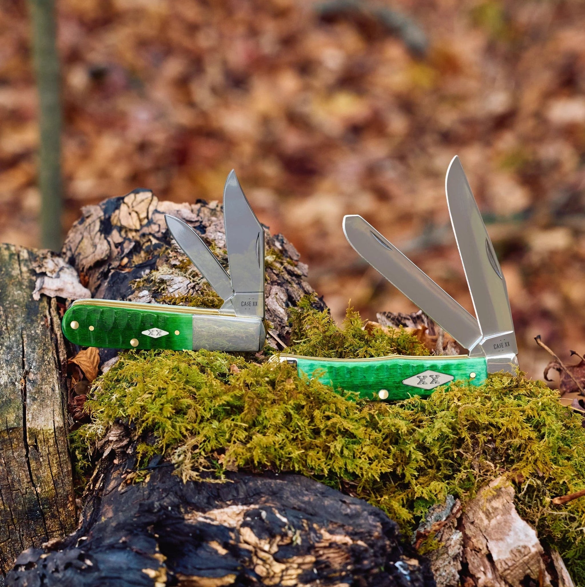 Two Case knives on a mossy log with a forest floor background