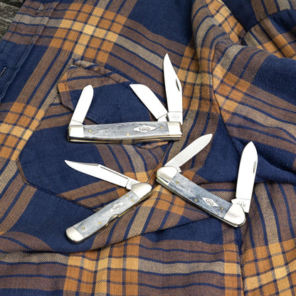 Lifestyle image of three Smooth Gray Bone knives laying on a flannel shirt.