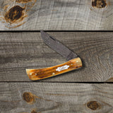 Second Cut Jig Burnt Goldenrod Damascus Sod Buster Jr® on a Wooden Background 