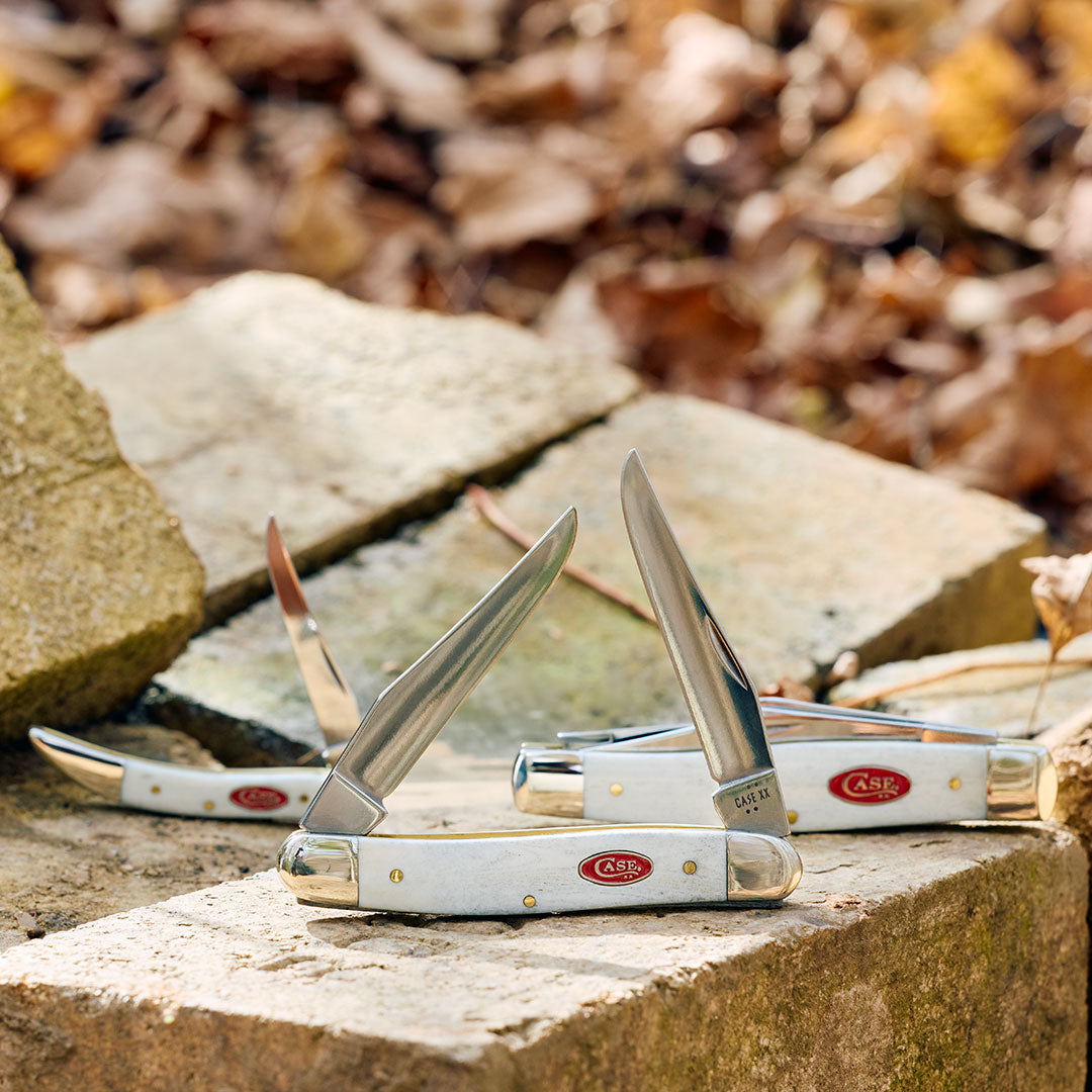 Smooth Natural Bone handle folding knives on a stone surface with a natural background