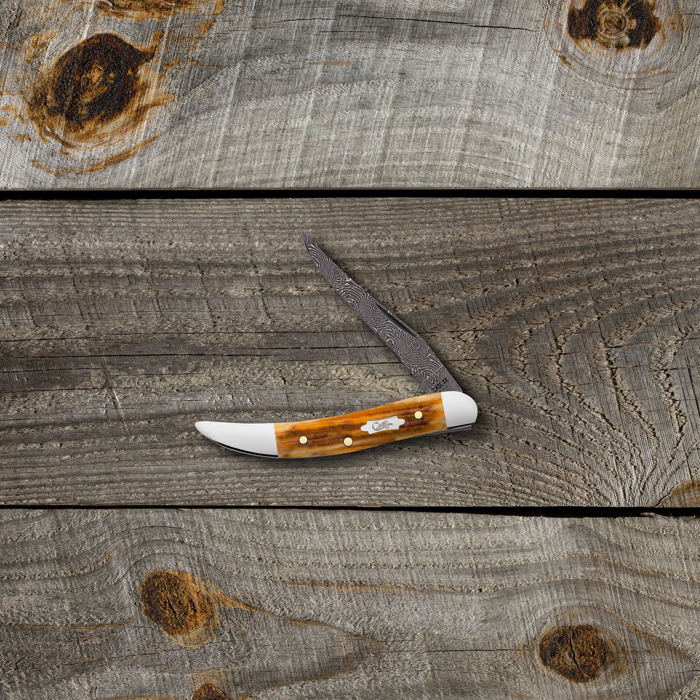 Second Cut Jig Burnt Goldenrod Damascus Medium Texas Toothpick on a Wooden Background