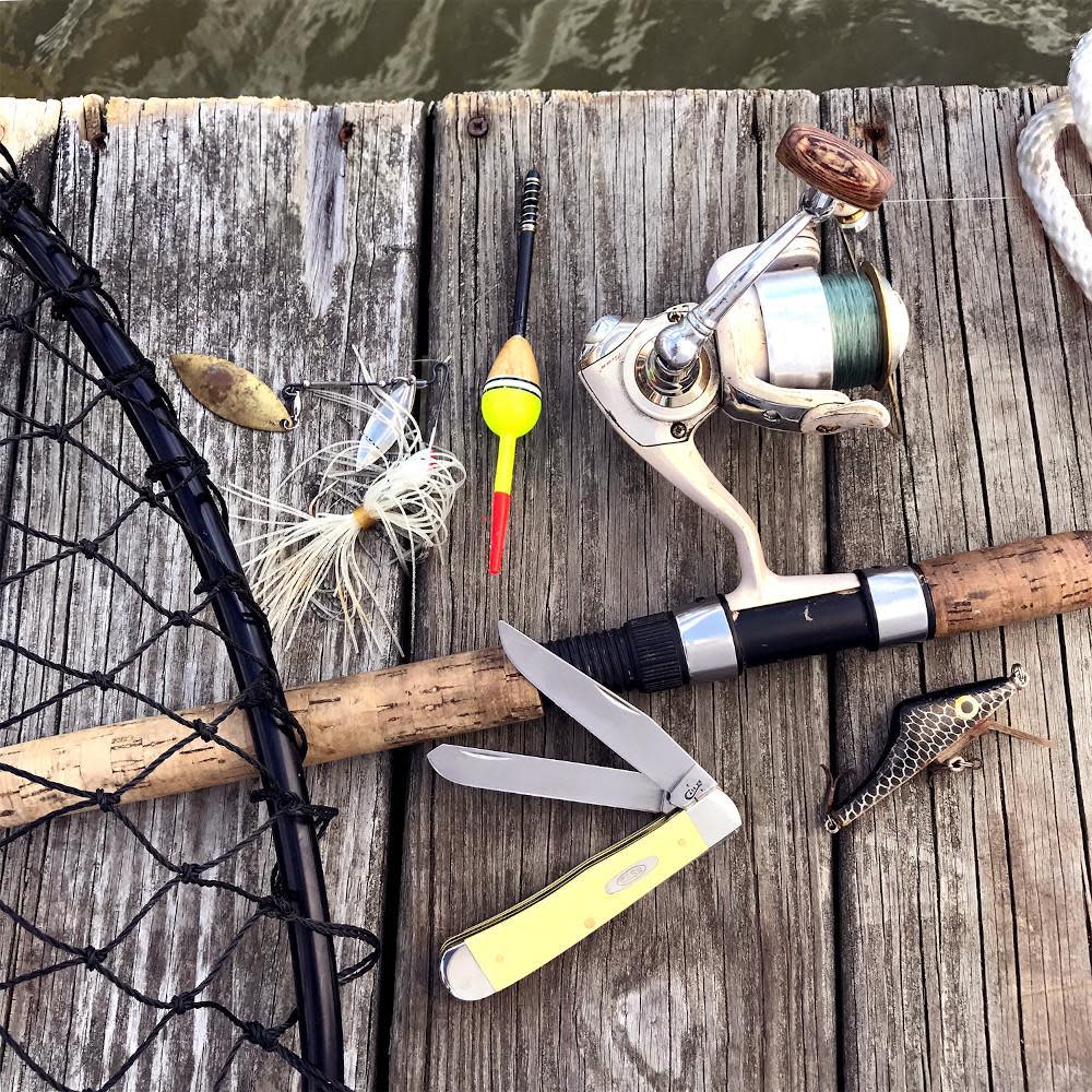 Smooth Yellow Synthetic CS Trapper Knife on a dock with fishing equipment
