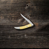 Yellow Synthetic Small Texas Toothpick Knife on Wood Background