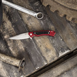 Red Anodized Aluminum G-10 Marilla® Knife on a rusty metal background