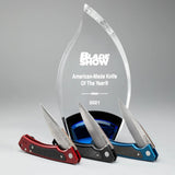 Red Anodized Aluminum G-10 Marilla® Knife in front of the Blade Show American-Made Knife of the Year Award