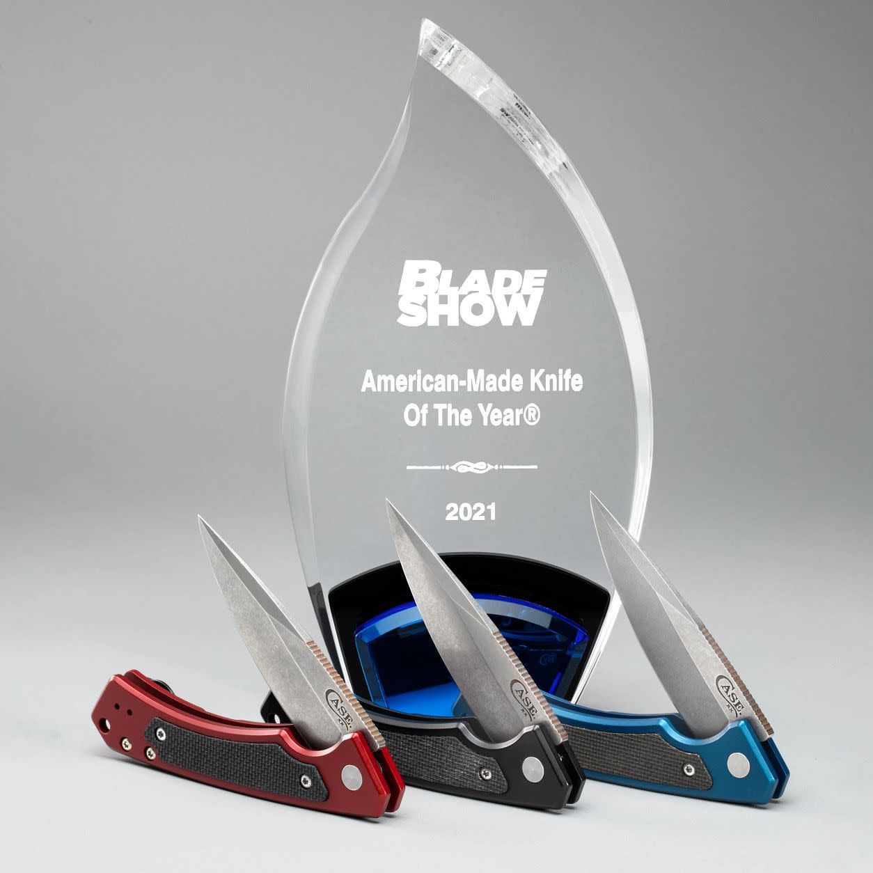 Blue Anodized Aluminum G-10 Marilla® Knife in front of the Blade Show American-Made Knife of the Year Award