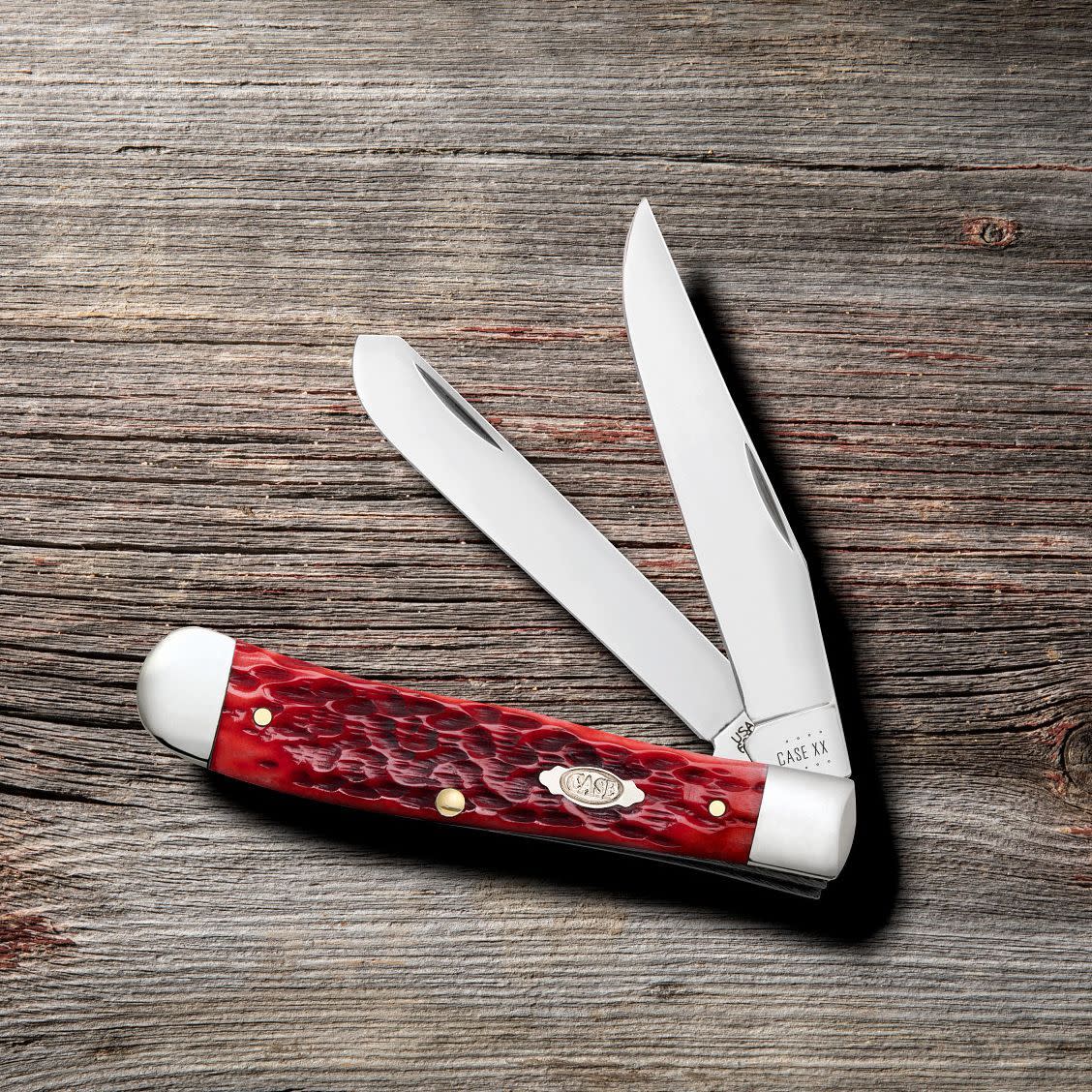 Peach Seed Jig Dark Red Bone CS Trapper Knife on Wooden Background