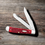 Peach Seed Jig Dark Red Bone CS Trapper with Pocket Clip Knife on Wooden Background