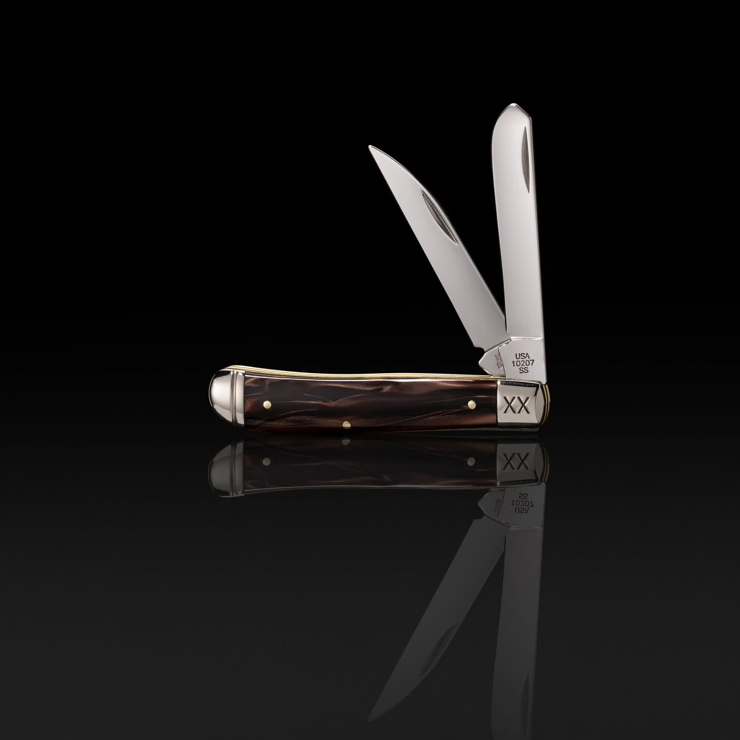 Front view of the Smooth Caramel Swirl Kirinite® Mini Trapper showing the Clip and Wharncliffe blades standing in front of a black background